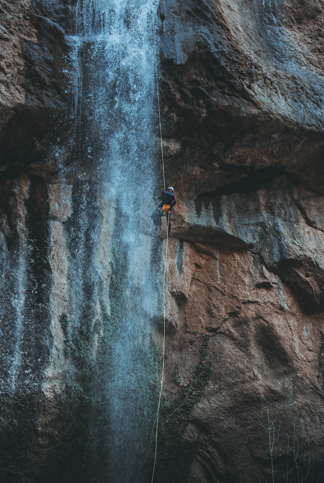 Background by Surf Brands person in blue jacket climbing on rocky mountain during daytime