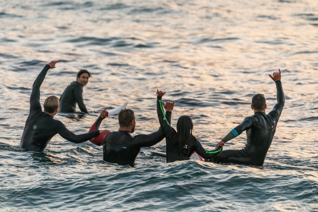 FAQ by Surf Brands people wearing black wetsuits in body of water