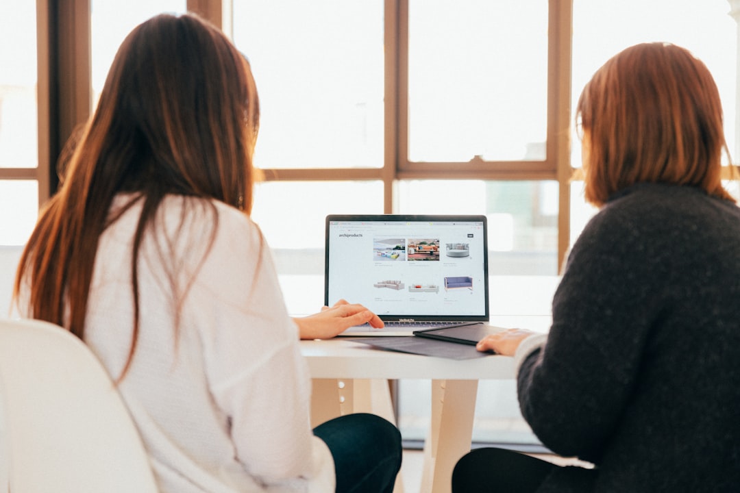 Searching by Surf Brands two women talking while looking at laptop computer