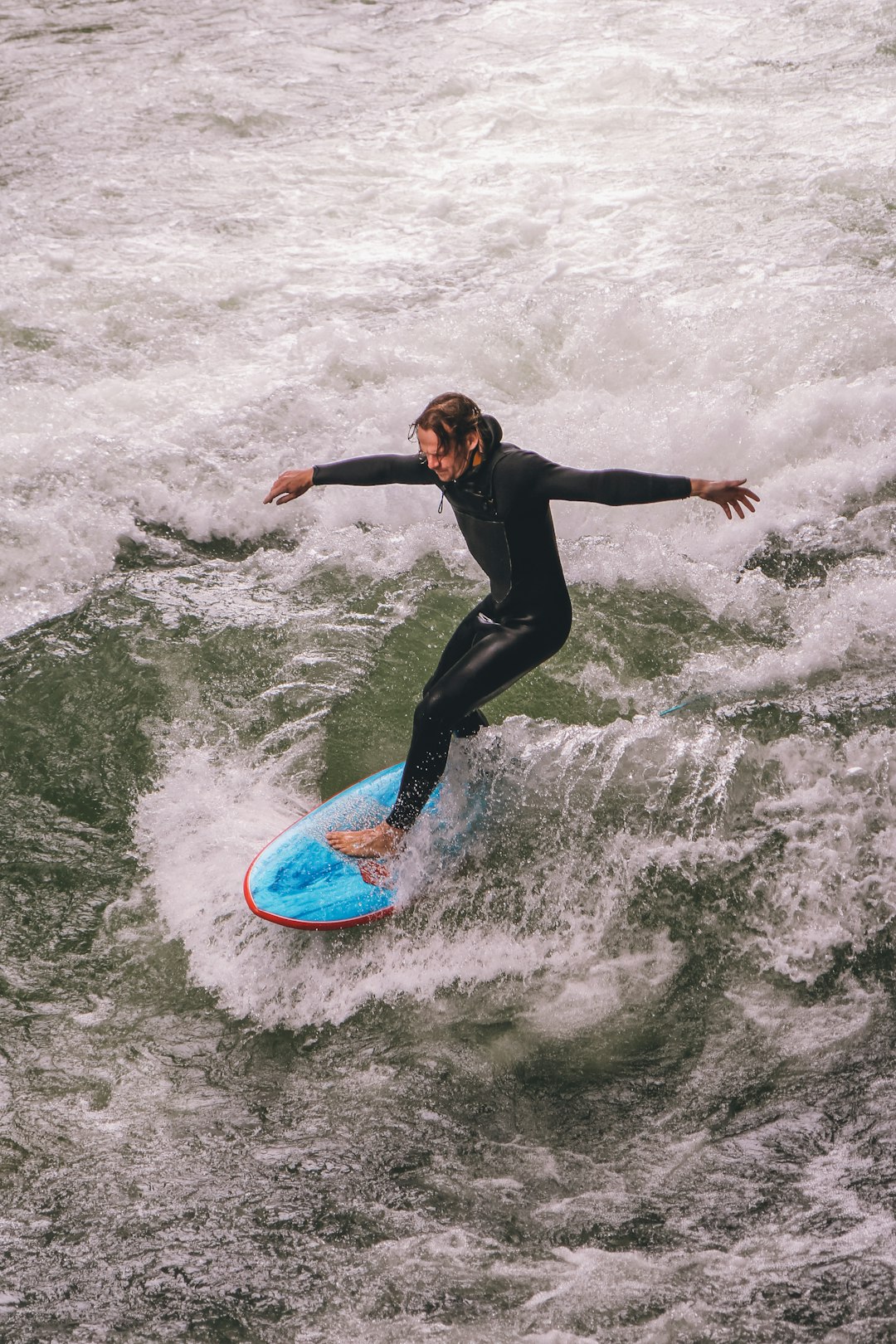 A surfer enjoying the unique experience of river surfing in the middle of the city of Munich 🌊 by Surf Brands a man riding a surfboard on top of a wave